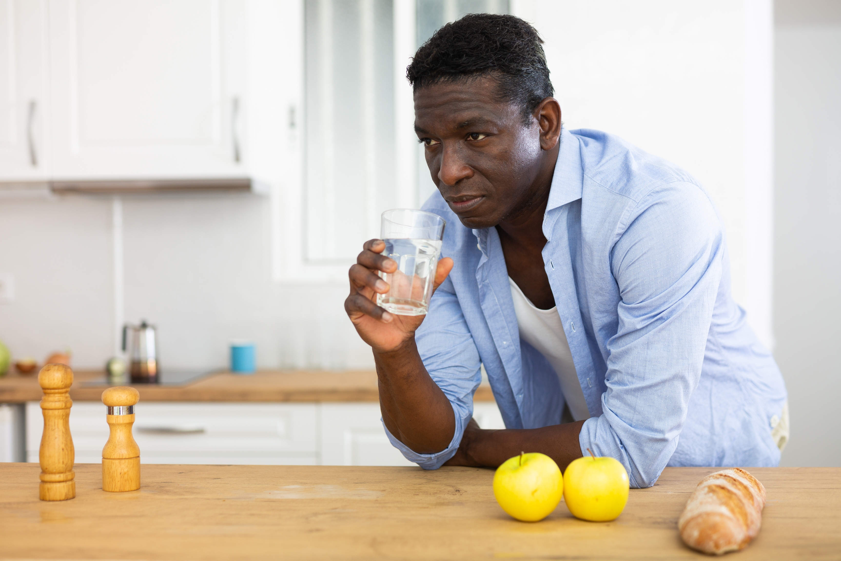 Man drinking glass of water in kitchen