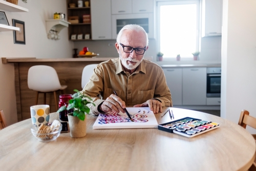 Man sitting at kitchen table painting in canvas